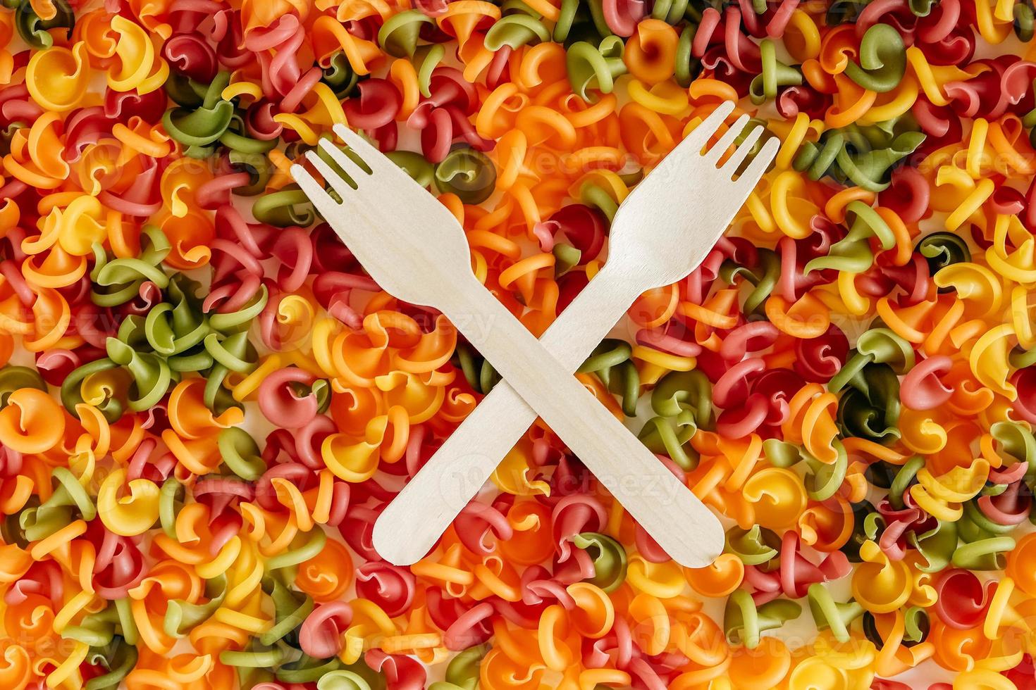 Multicolored pasta with a wooden forks as a background image. Top view. Copy, empty space for text photo