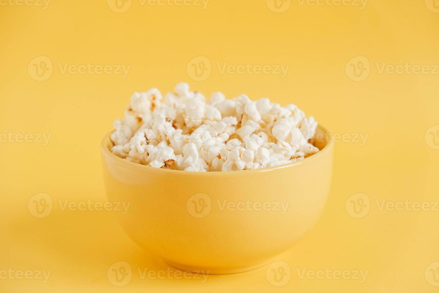 Popcorn in a yellow bowl on a yellow background. Copy, empty space for text photo