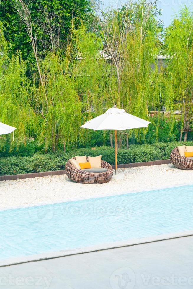outdoor patio chair with pillow and umbrella around swimming pool photo