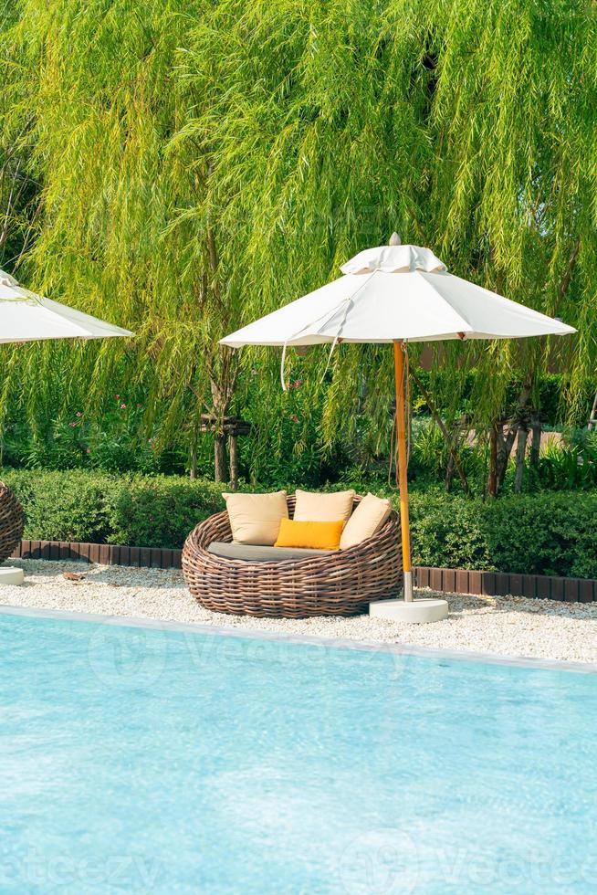 outdoor patio chair with pillow and umbrella around swimming pool photo