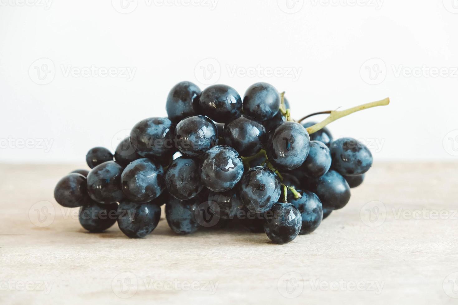One bunch of freshly picked black grapes on a old wooden table photo