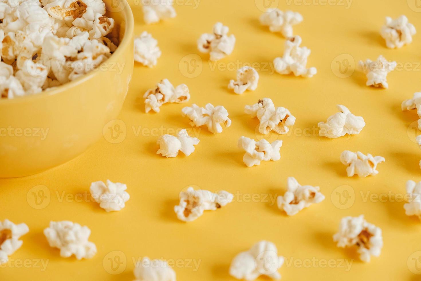 Popcorn in a yellow bowl on a yellow background. Top view. Copy, empty space for text photo