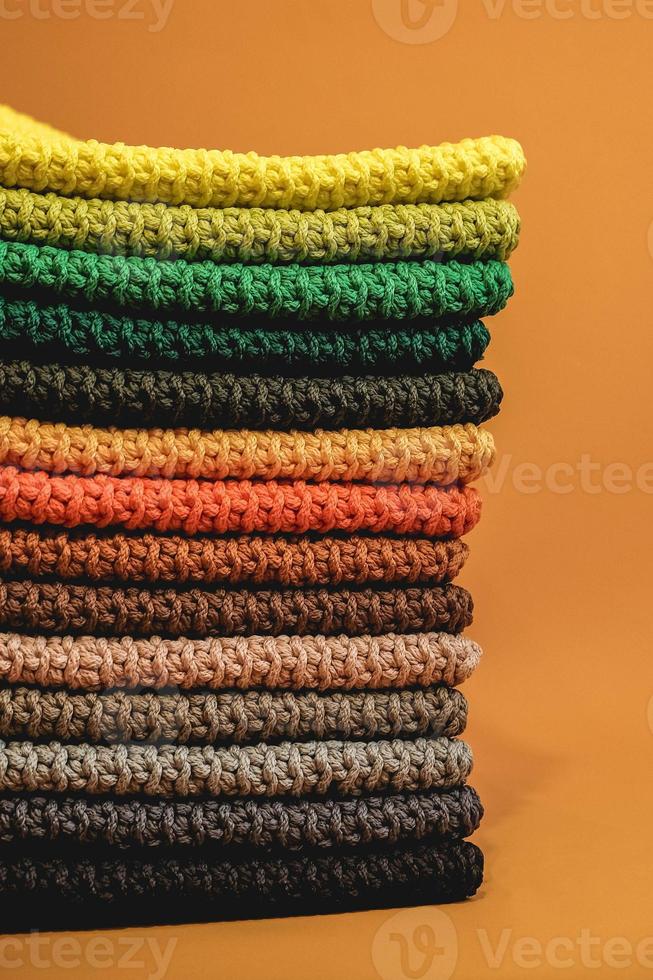 Stack of knitted material from multicolored threads on a orange background. Copy, empty space for text photo