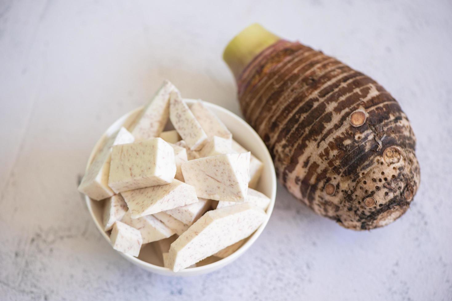 Taro root with slice cubes on bowl and table background, Fresh raw organic taro root ready to cook photo