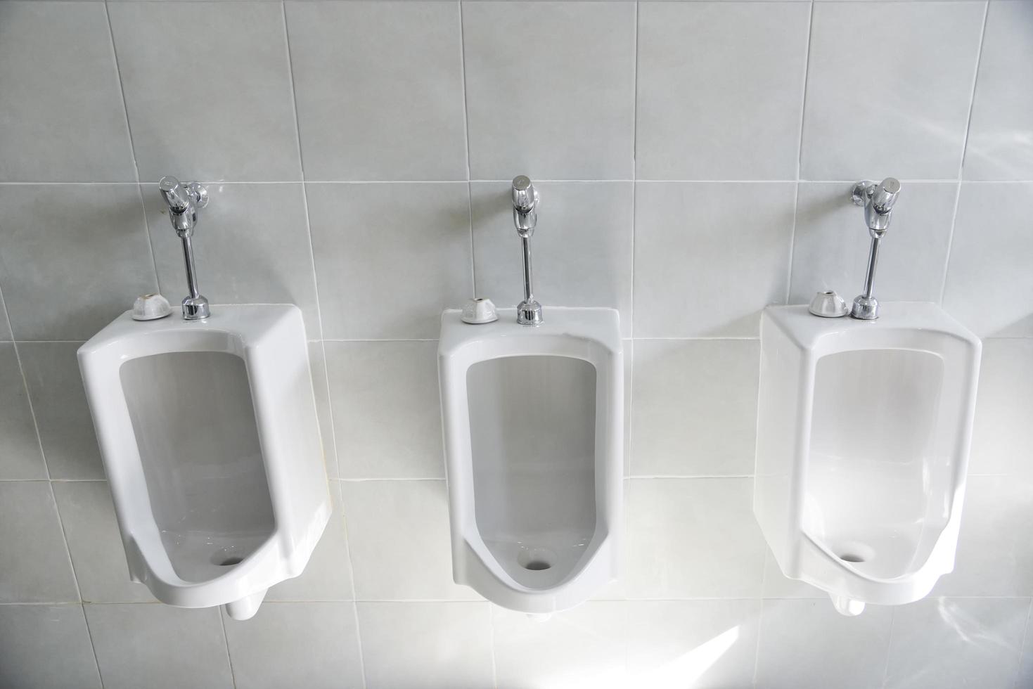 Row of urinal toilet blocks for man on tiled wall in public toilet photo