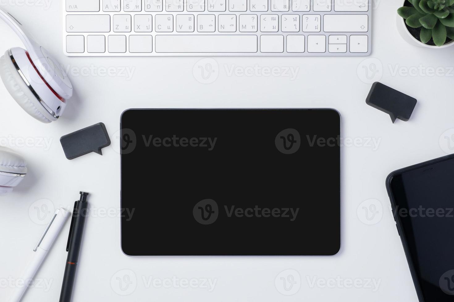 top view working desk with keyboard headphone and tablet on white table background photo