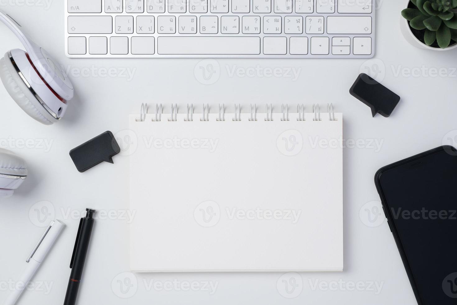 top view working desk with keyboard headphone and open notebook on white table background photo