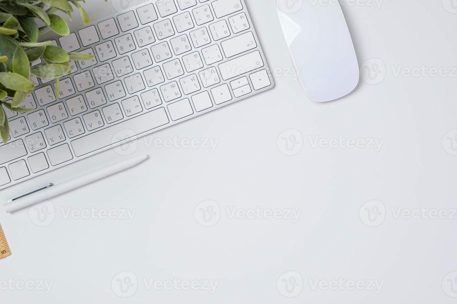 escritorio de trabajo de vista superior con teclado, mouse y portátil en el fondo de la mesa blanca foto