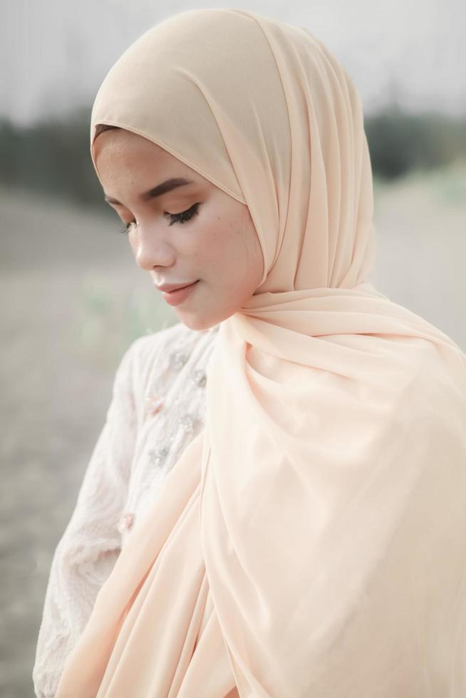 Beautiful islamic female model wearing hijab fashion, a modern wedding dress for muslim woman walks along the sand and the sea. A asian girl model using hijab having fun at the beach. Photo prewedding