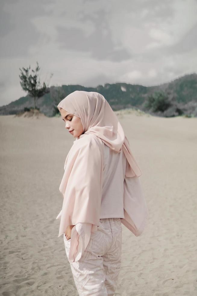 Beautiful islamic female model wearing hijab fashion, a modern wedding dress for muslim woman walks along the sand and the sea. A asian girl model using hijab having fun at the beach. Photo prewedding