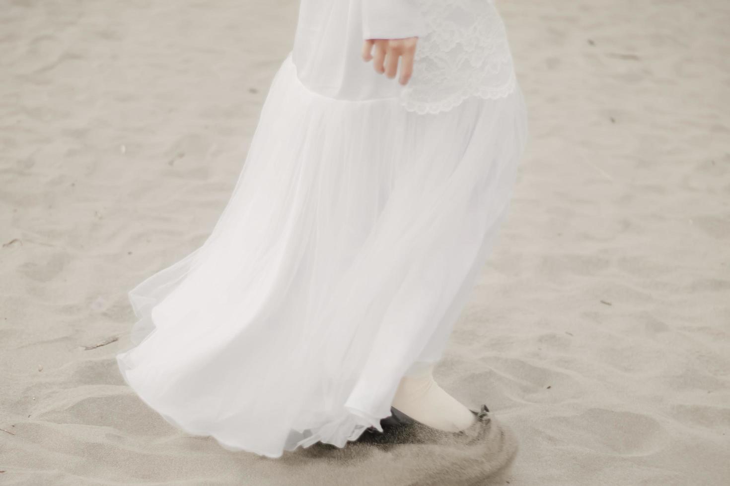 hermosa modelo femenina islámica con moda hijab, un vestido de novia moderno para mujeres musulmanas camina por la arena y el mar. una modelo asiática usando hijab divirtiéndose en la playa. foto preboda