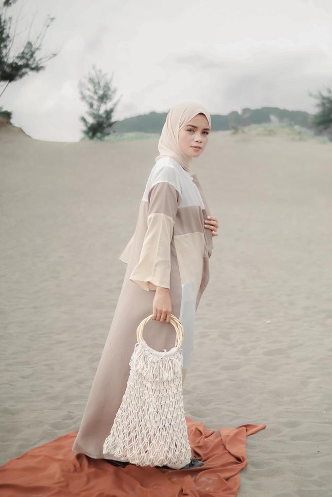 Beautiful islamic female model wearing hijab fashion, a modern wedding dress for muslim woman walks along the sand and the sea. A asian girl model using hijab having fun at the beach. Photo prewedding