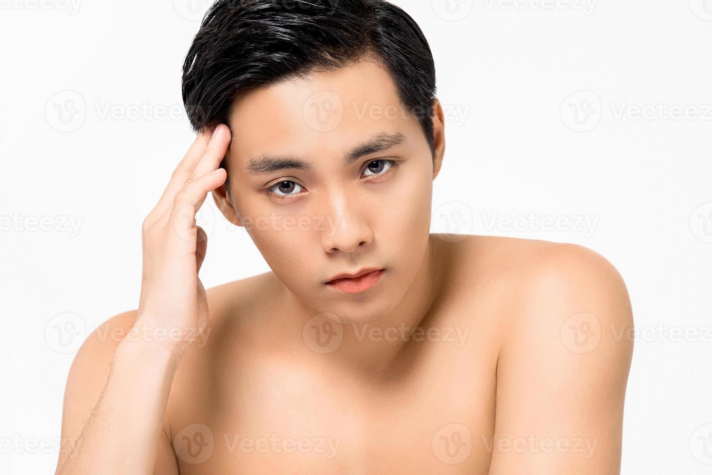 Shirtless young handsome Asian man with hand touching head isolated on white background for skin care and beauty concepts photo