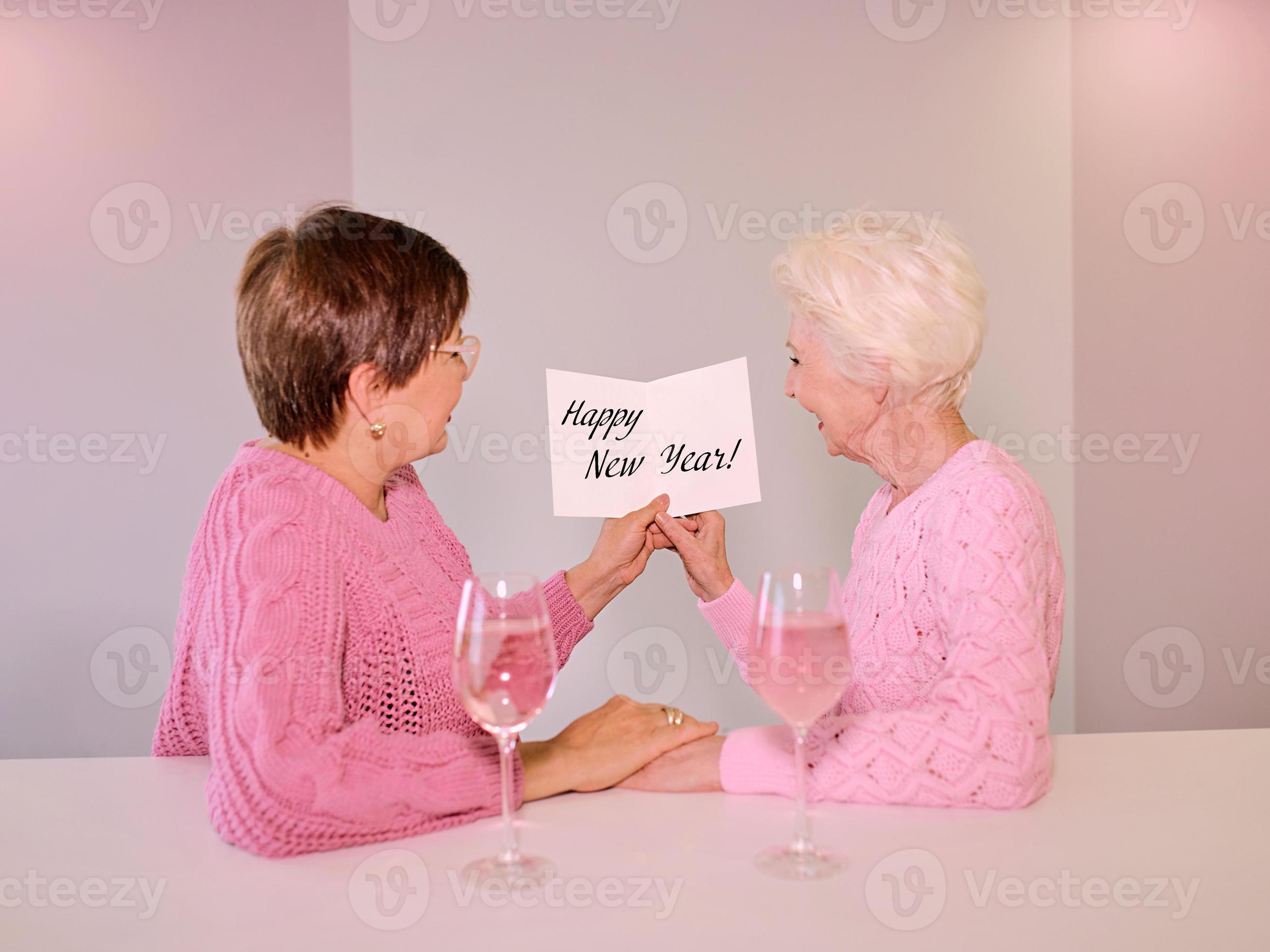 Two mature women drinking wine and giving a post card picture