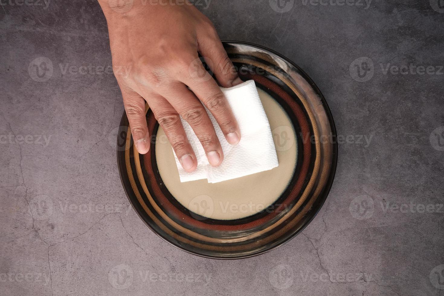 close up of young man wiping plate with a cloth photo
