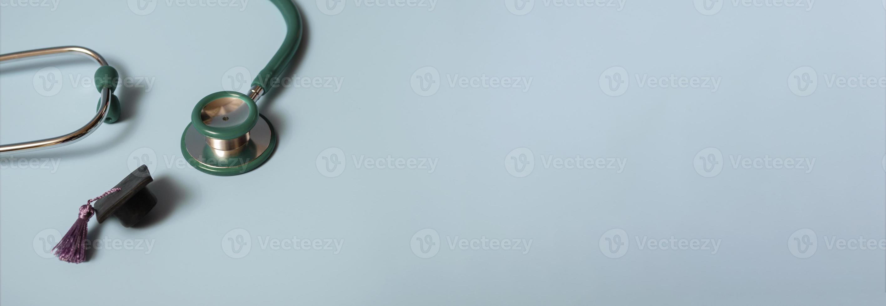 Graduation cap with stethoscope and numbers 2022 on blue background, closeup with copy space. Medical education concept. photo