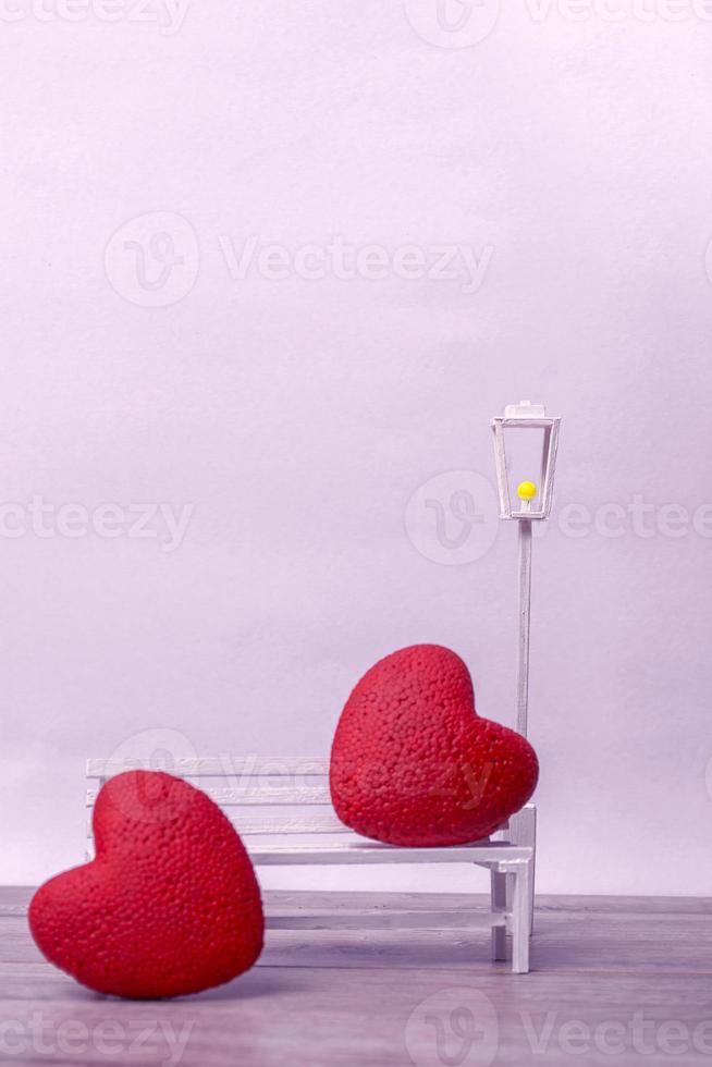Pair of hearts on a white bench on a light background. Love concept, closeup with copy space. Vertical Format photo