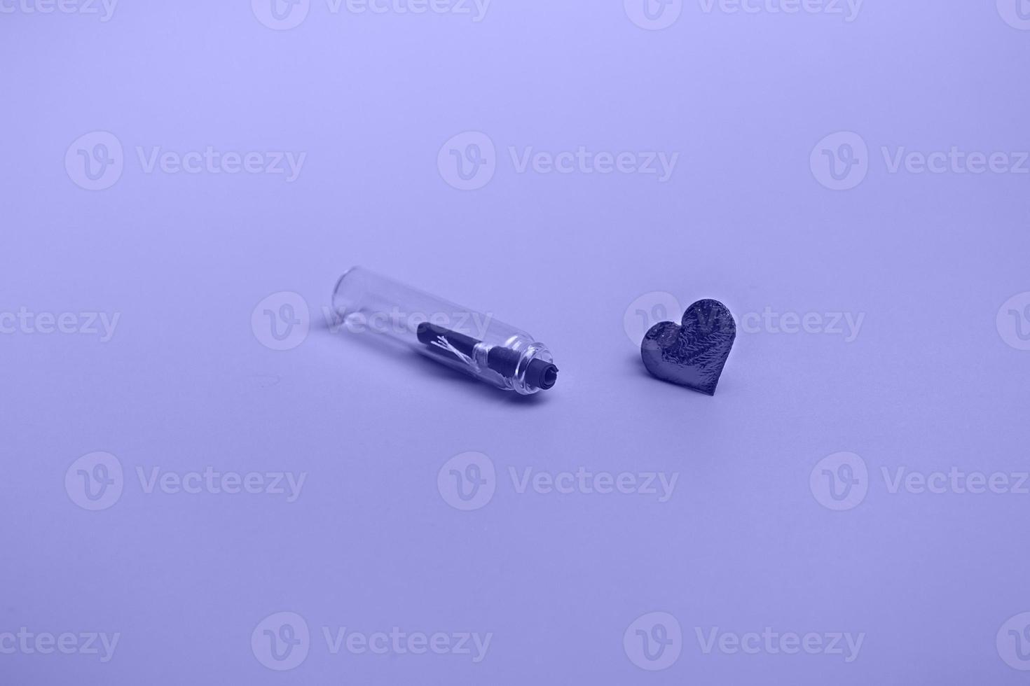 Message in a bottle on a very peri background with a heart. Holiday concept. Closeup with copy space photo