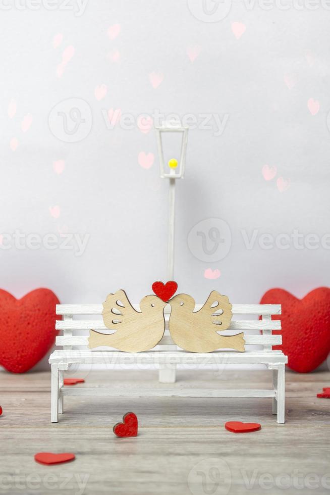 A pair of doves with a heart on a white bench. Love concept, closeup with copy space. Vertical Format photo