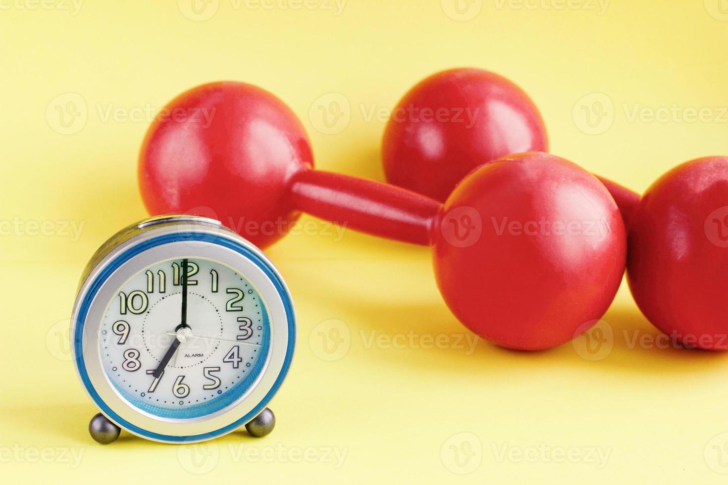 Time for exercising concept. alarm clock and dumbbell with colorful background photo