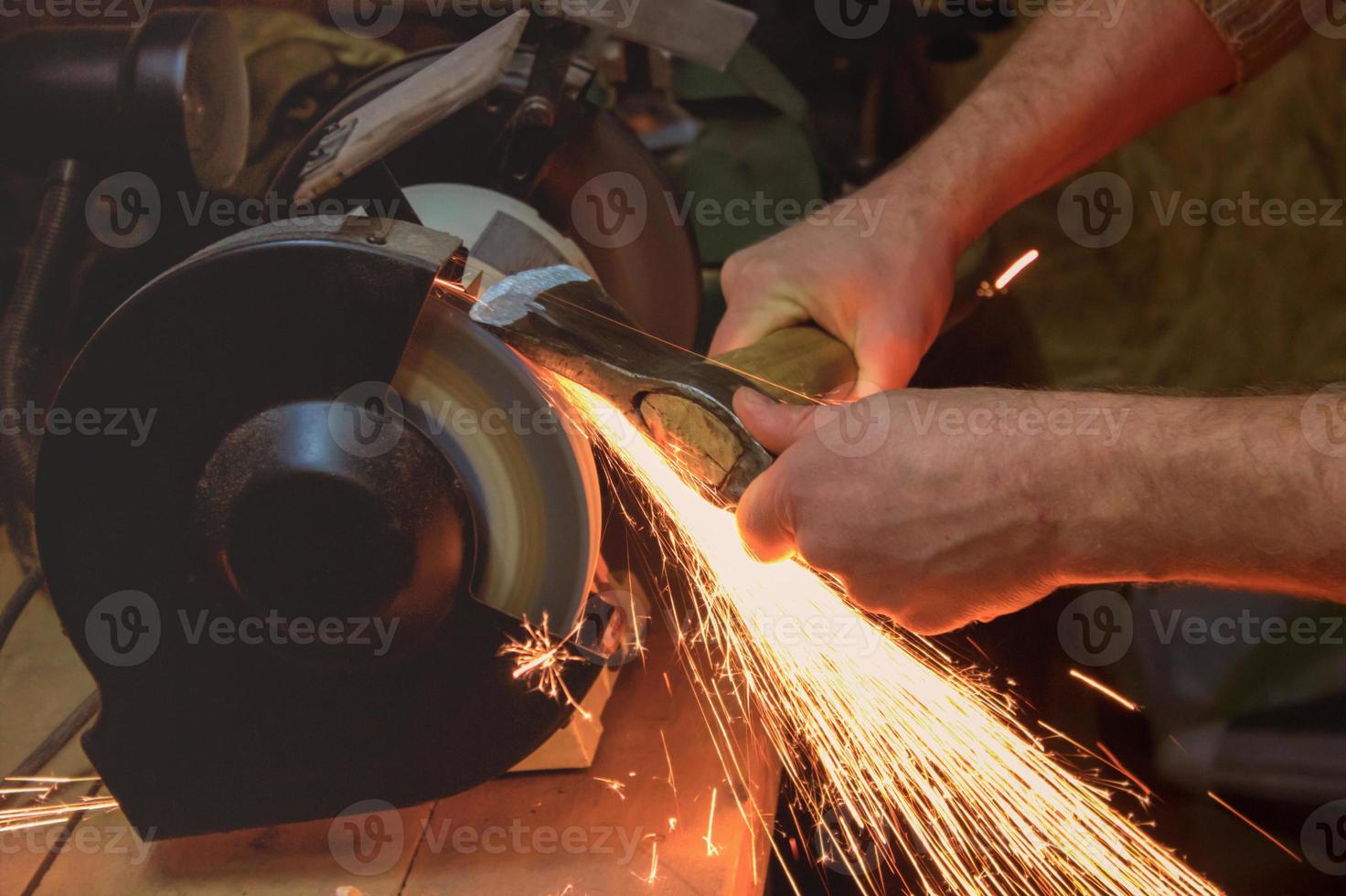 axe sharpener and hand with blade on wooden table, closeup photo