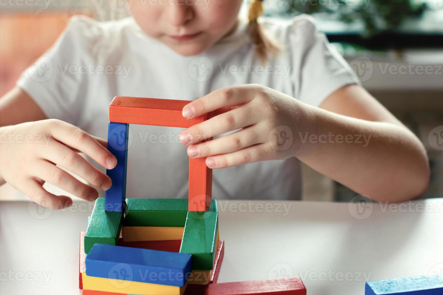 niña rubia jugando juegos de mesa. bloques de construcción de madera en manos de niña. foto