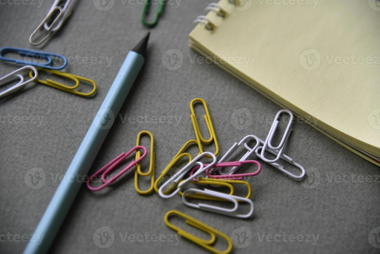Pencils notepad and paper clips on the office desk photo