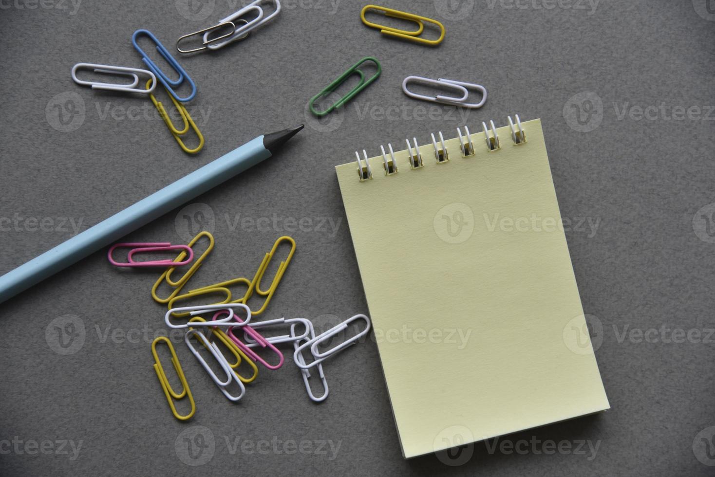 Pencils notepad and paper clips on the office desk photo