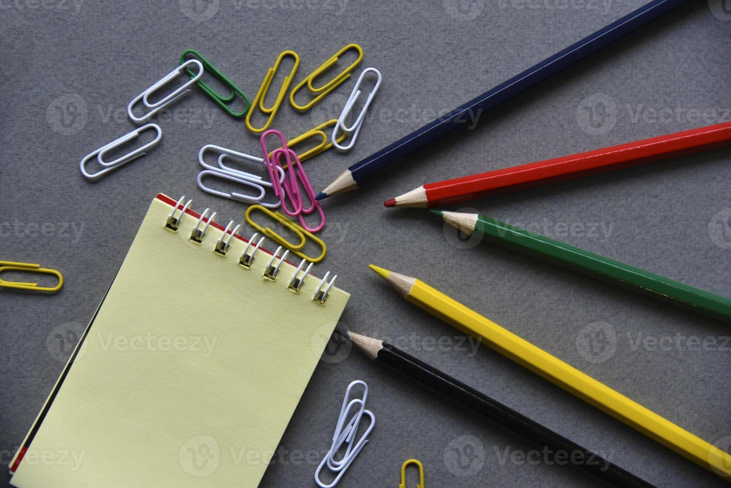 lápices, bloc de notas y clips de papel en el escritorio de la oficina foto