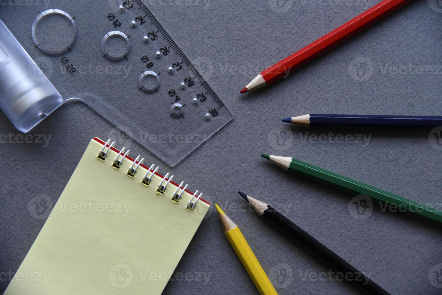 Pencils notepad and paper clips on the office desk photo