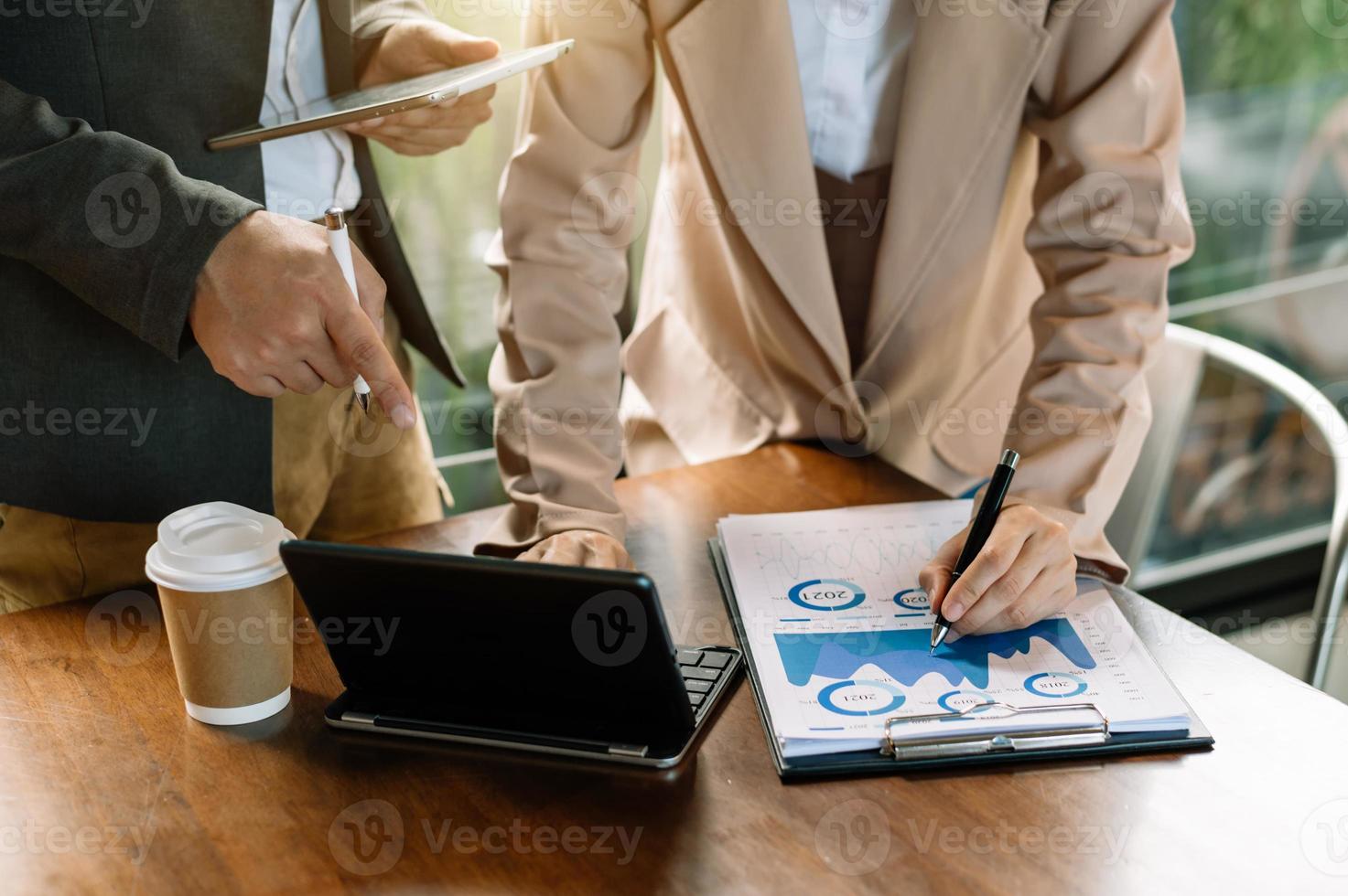 Business documents on office table with smart phone and calculator digital tablet and graph business with social network diagram and two colleagues discussing data working photo
