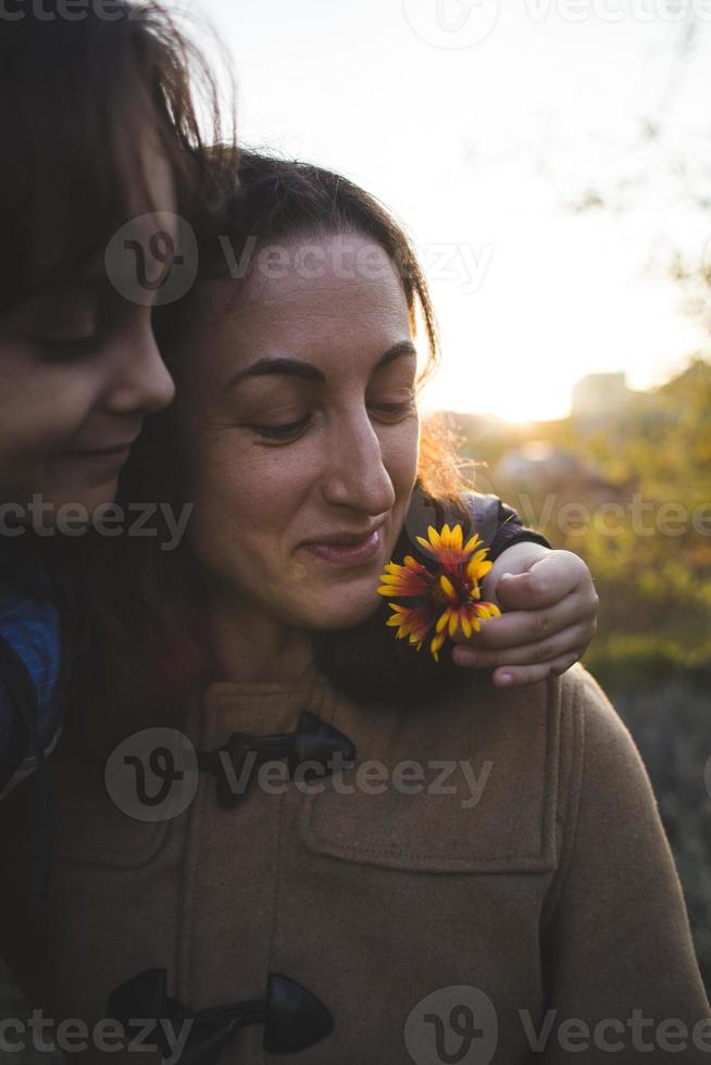 un niño le da una flor a su madre foto