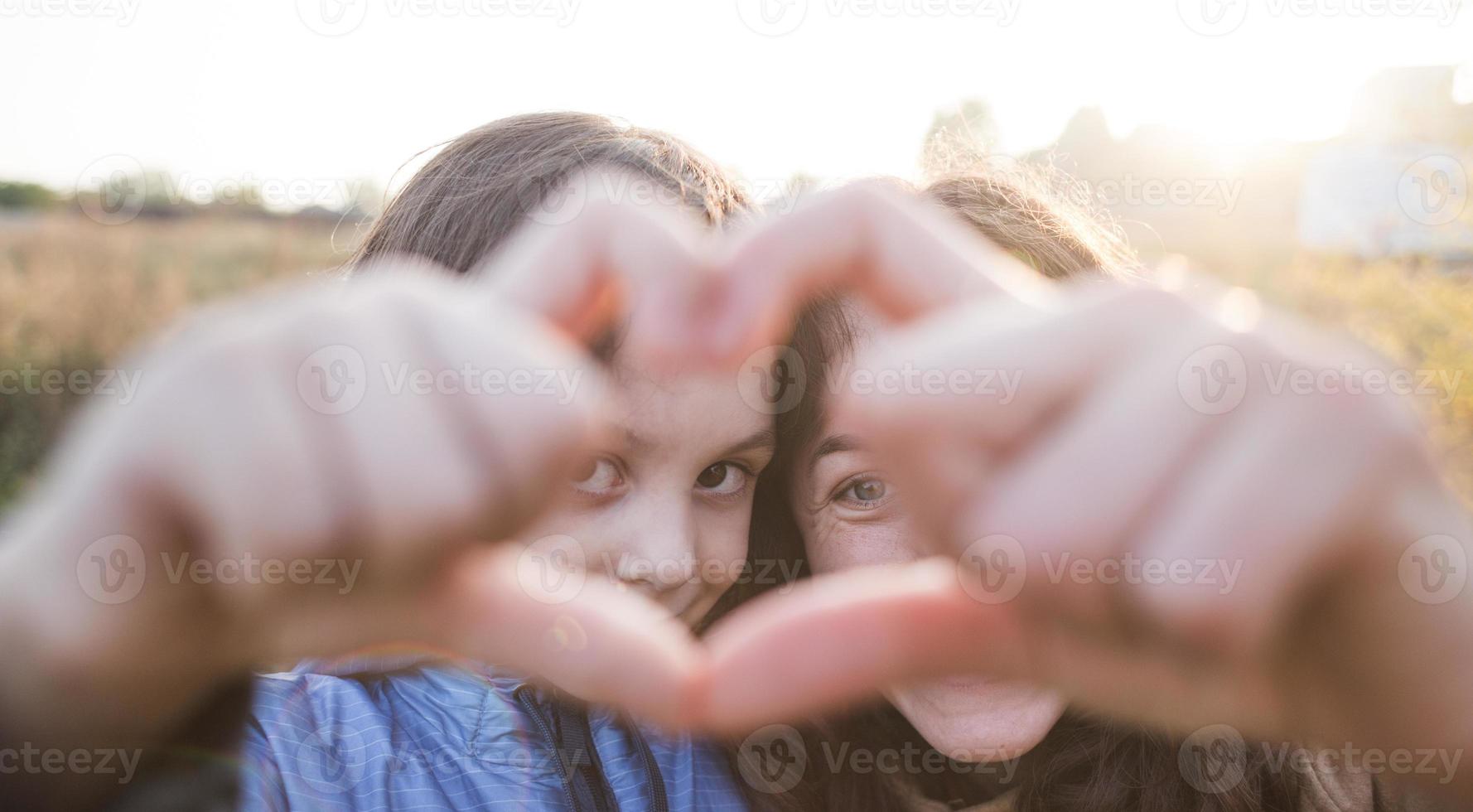 Boy with mom folded fingers in the shape of a heart. photo