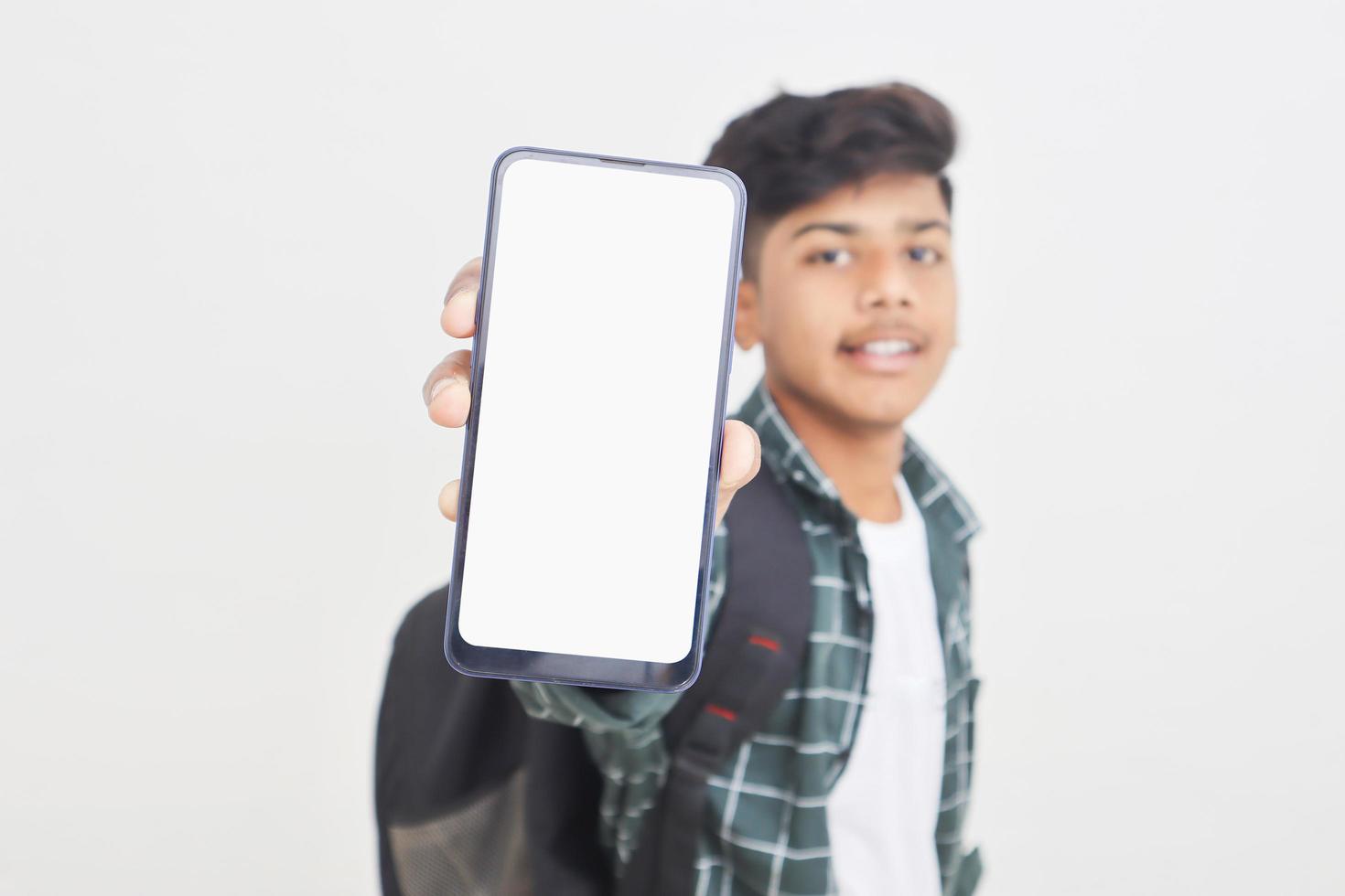 Young indian college student showing smartphone Screen on white background. photo