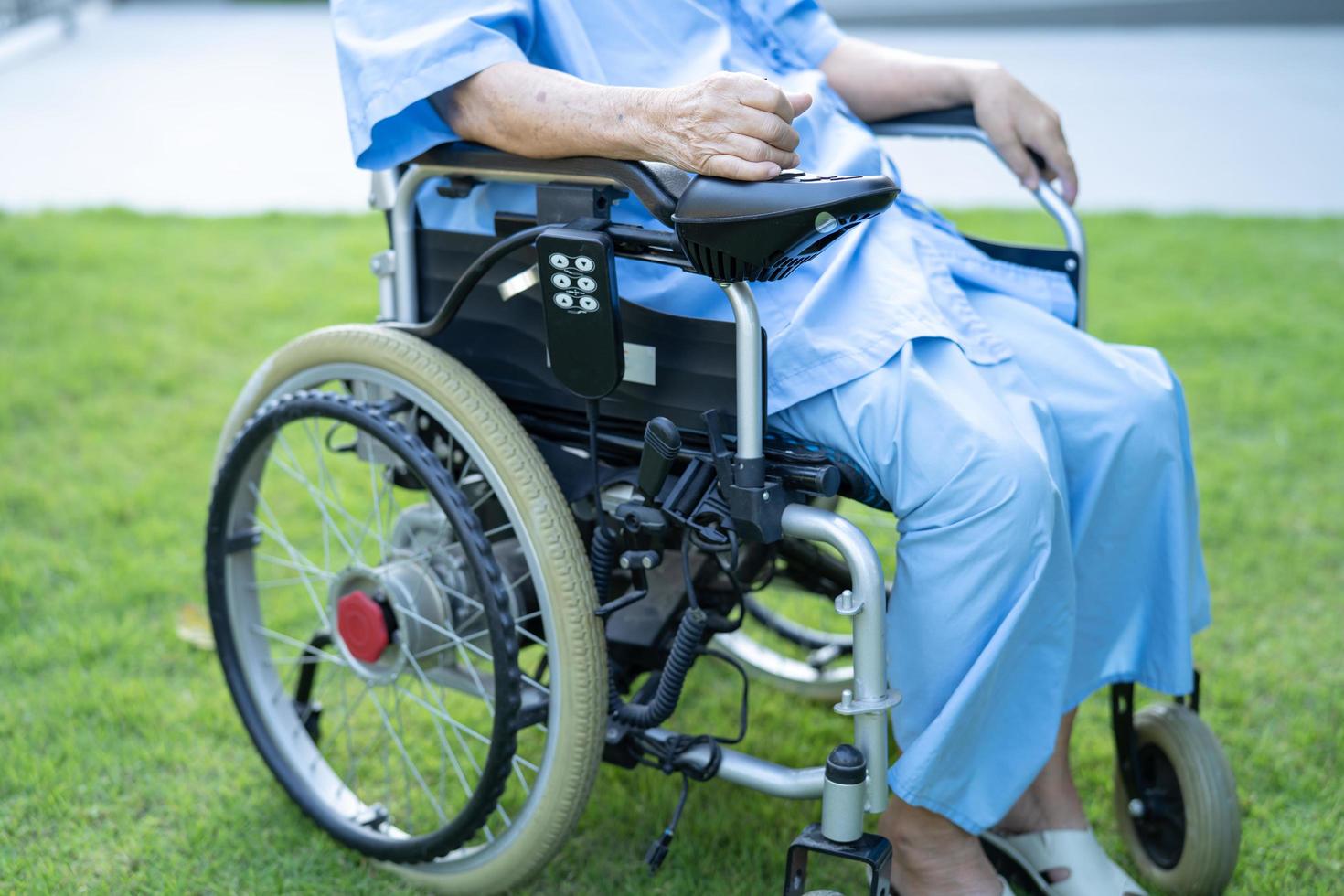 Paciente asiático mayor o anciano en silla de ruedas eléctrica con control remoto en la sala del hospital de enfermería, concepto médico fuerte y saludable foto