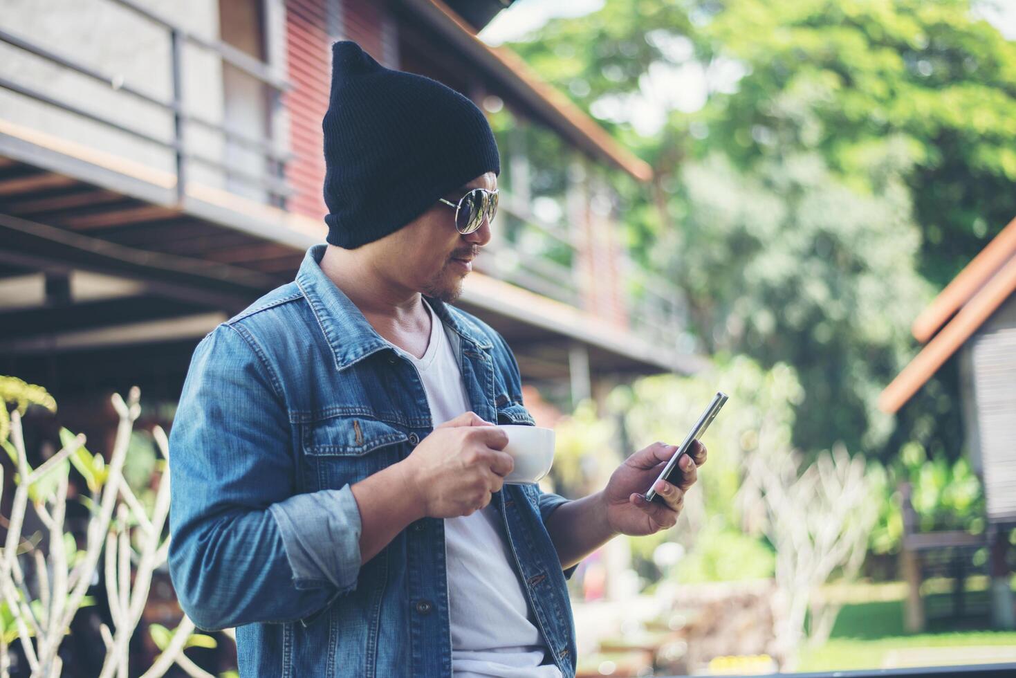 Hipster man resting at home balcony with the coffee cup in hand, Relaxing holiday concept. photo