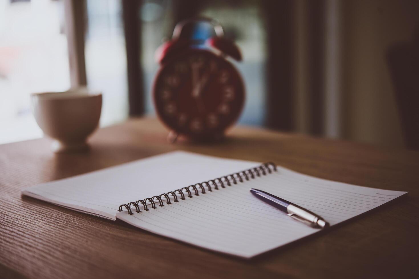 Vintage office desk table with notebooks, pen and a cup of coffee. With copy space. photo