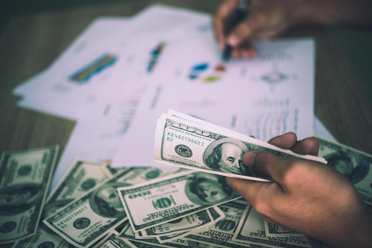 Working place of trader. The table covered by cash notes, keyboard and financial charts. Business financial working. photo