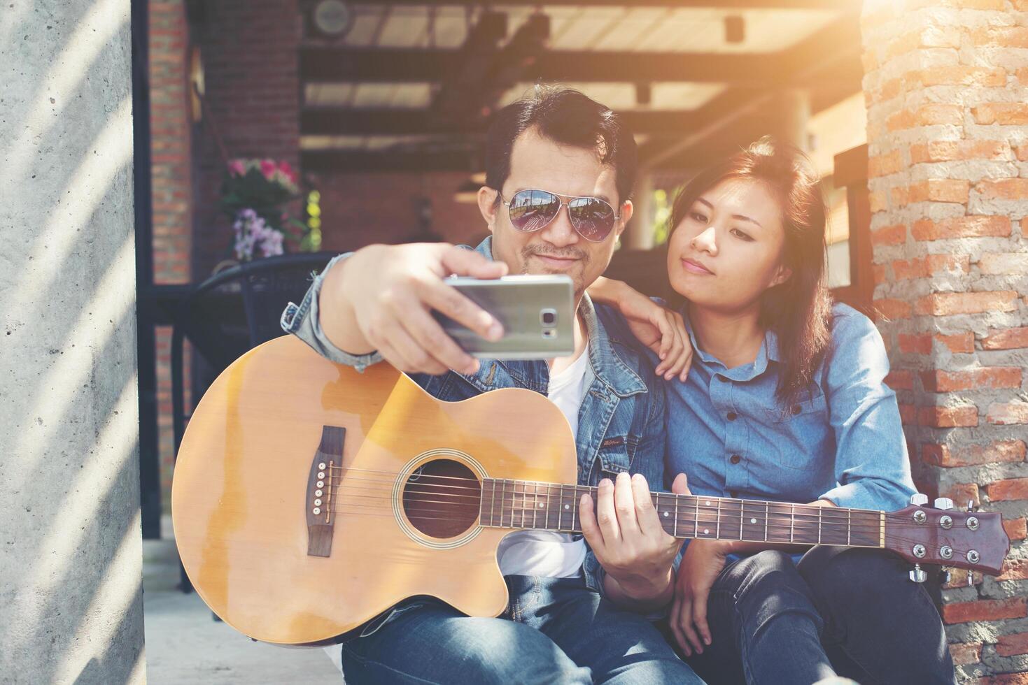 Hipster couple sitting relaxed with nice atmosphere with first date enjoys playing guitar as a great time together. photo