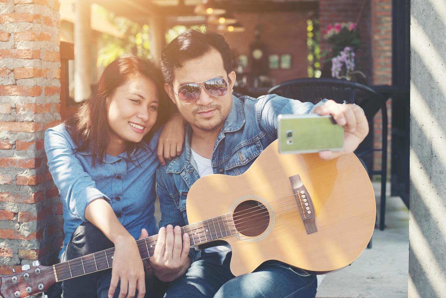 Hipster couple sitting relaxed with nice atmosphere with first date enjoys playing guitar as a great time together. photo