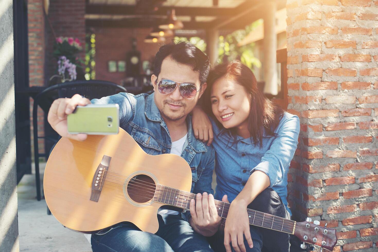 Hipster couple sitting relaxed with nice atmosphere with first date enjoys playing guitar as a great time together. photo