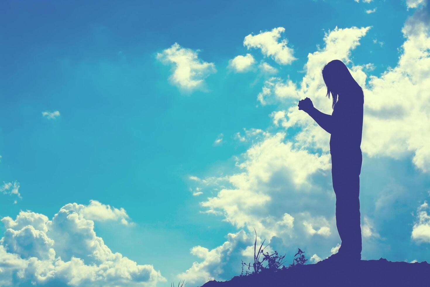 Silhouette of woman praying over beautiful sky background photo