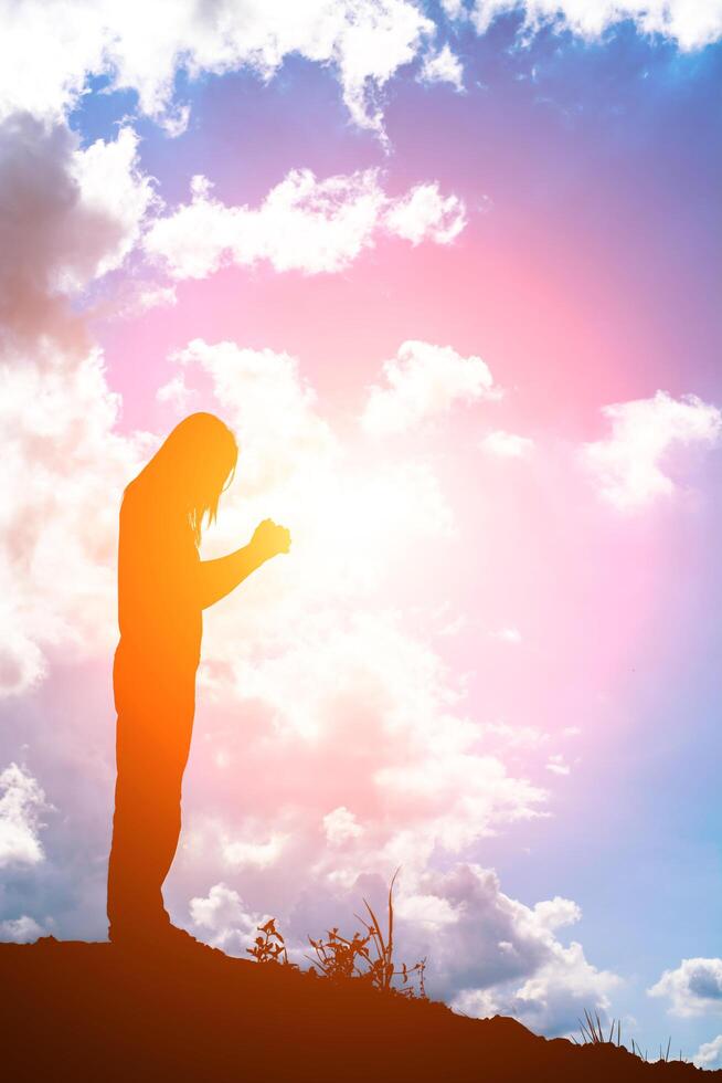 Silhouette of woman praying over beautiful sunrise background photo