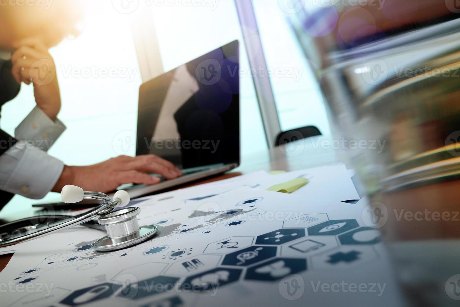 doctor en medicina trabajando a mano con una computadora moderna y un teléfono inteligente en un escritorio de madera como concepto médico foto