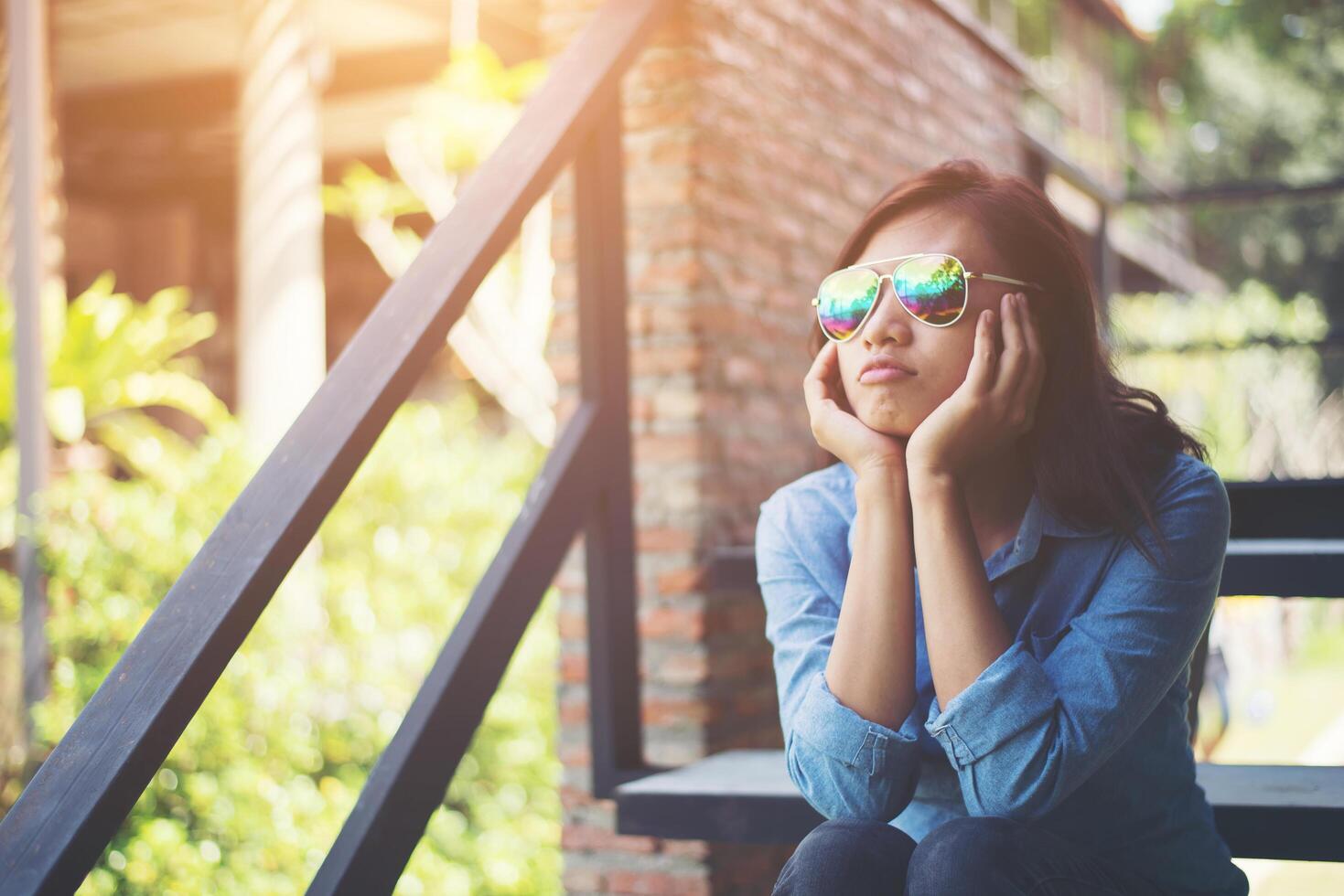 Young hipster woman sitting on staircase while looking away to outside. photo