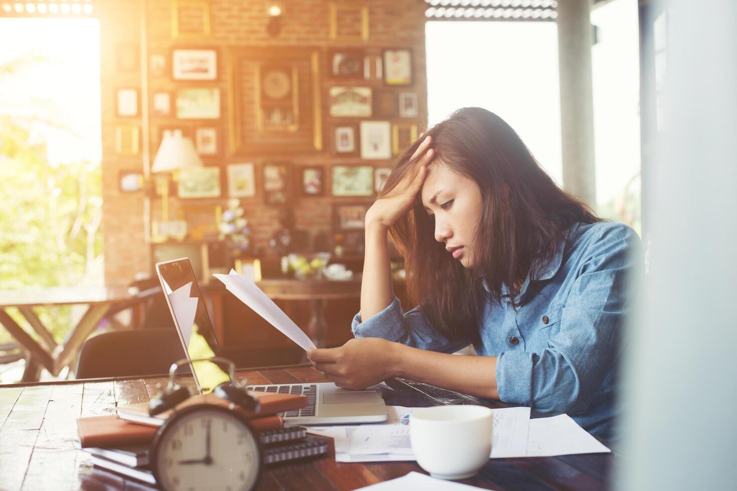 mujer joven sentada en un café con su computadora portátil, estresante para el trabajo. foto