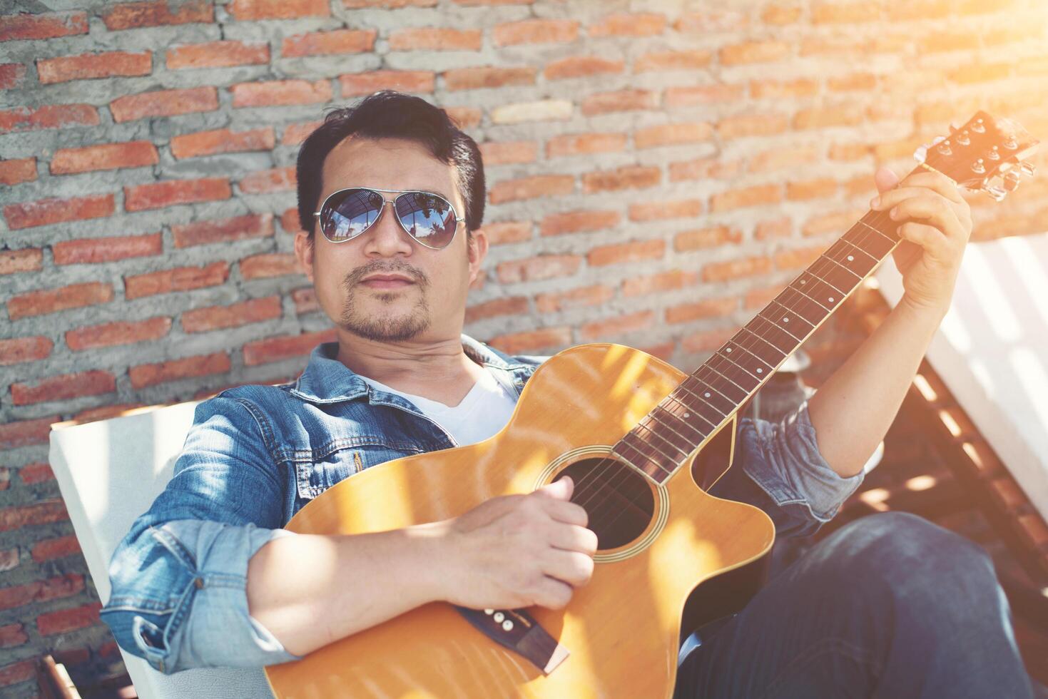Handsome hipster men practice to play guitar while he is enjoying the relaxing with nature around. photo