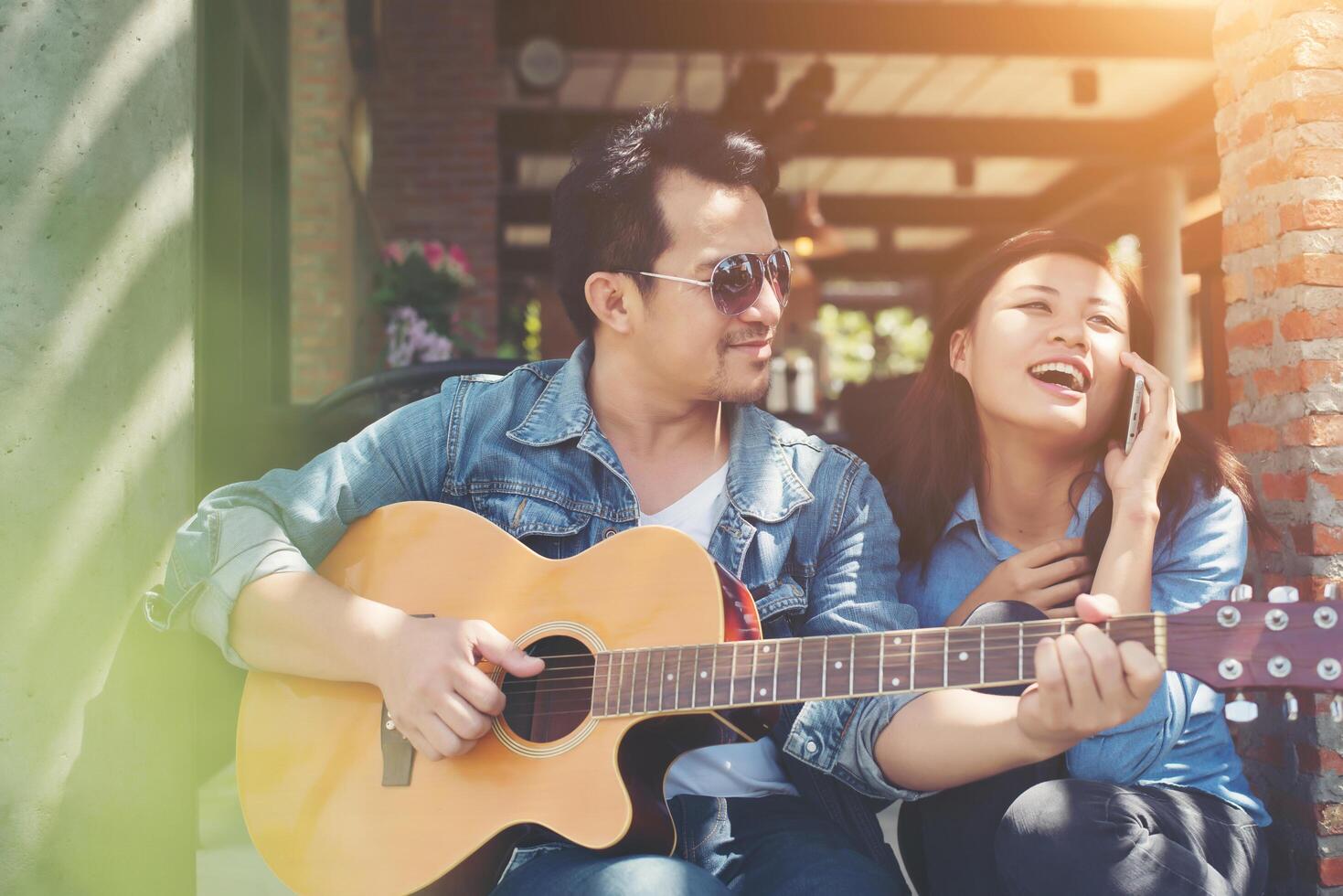 una pareja hipster sentada relajada con un ambiente agradable con la primera cita disfruta tocando la guitarra como un gran momento juntos. foto