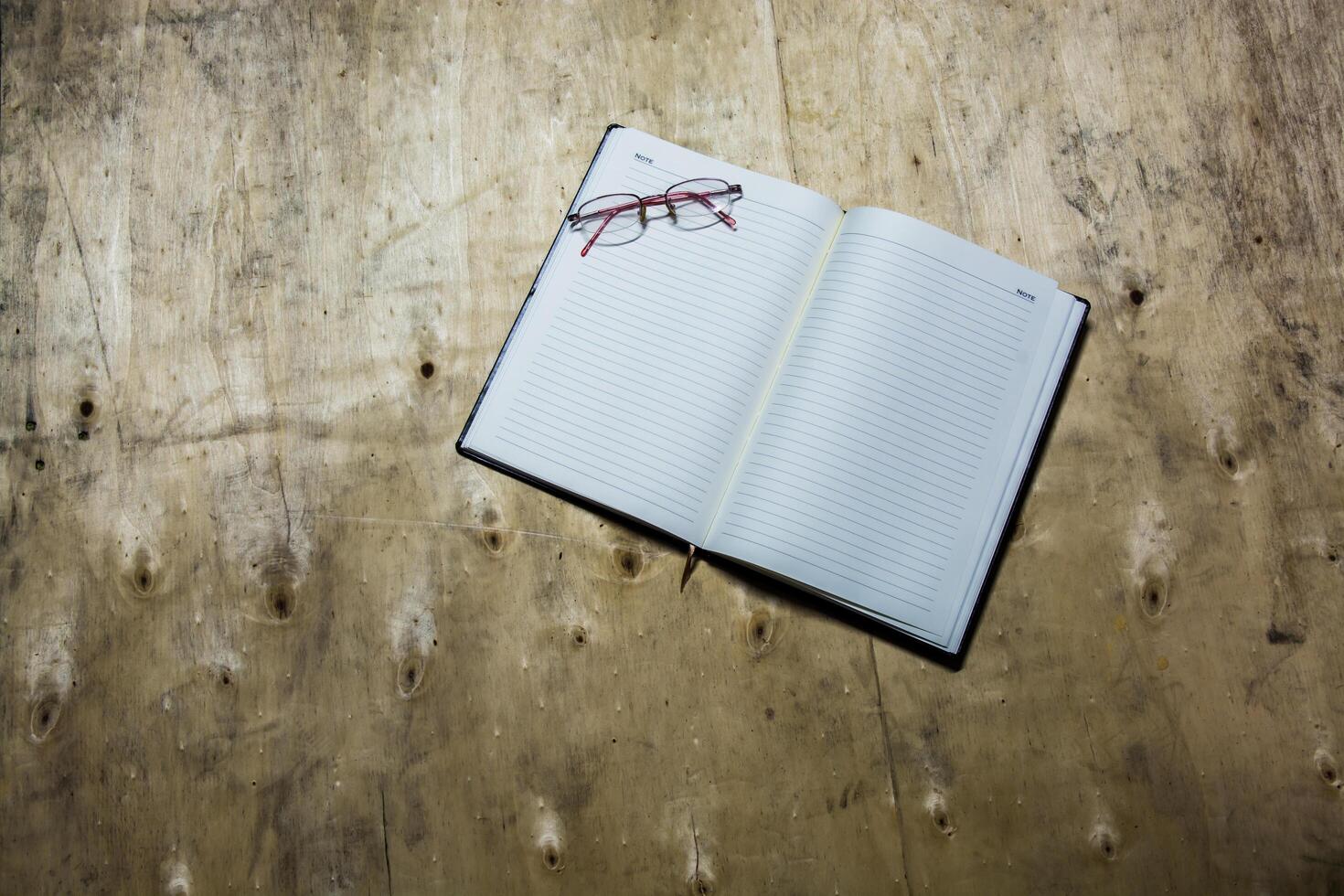 libreta vacía con gafas en un escritorio de madera. foto