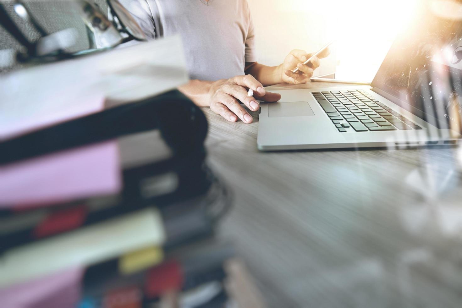 designer hand working with digital tablet and laptop and notebook stack and eye glass on wooden desk in office photo